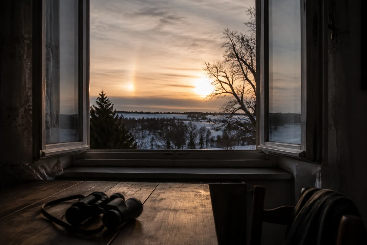 Illustration IA : Paysage hivernal et lumière du Soleil observés depuis une fenêtre ouverte.
