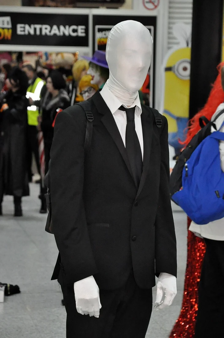 Personne costumée en Slender Man, visage blanc et costume noir, lors d’une convention à Londres.