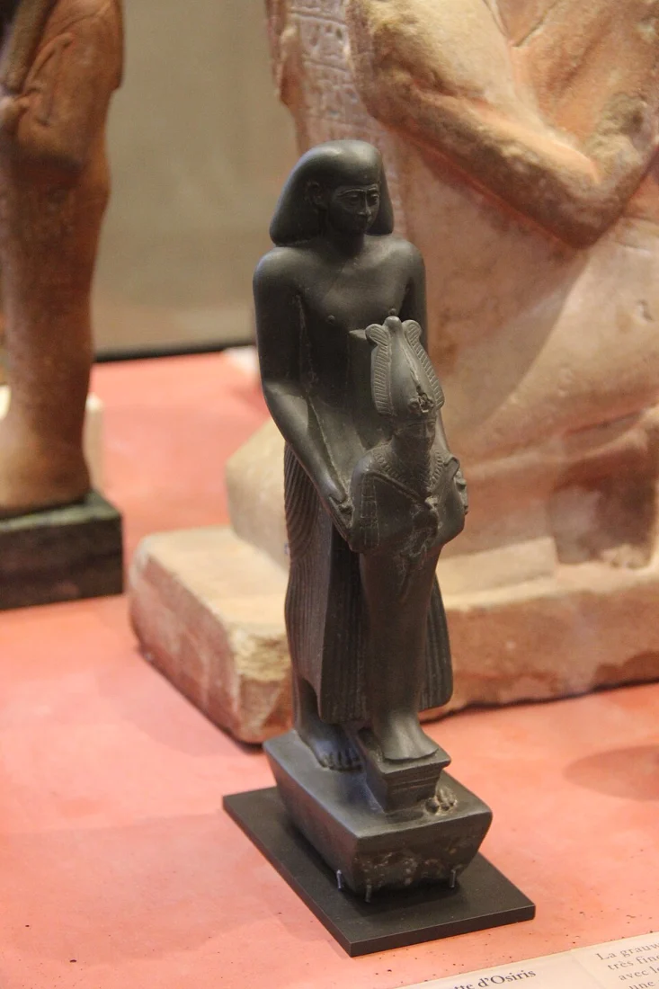 Statue sombre d’Osiris debout, présentée dans les collections égyptiennes du Louvre.