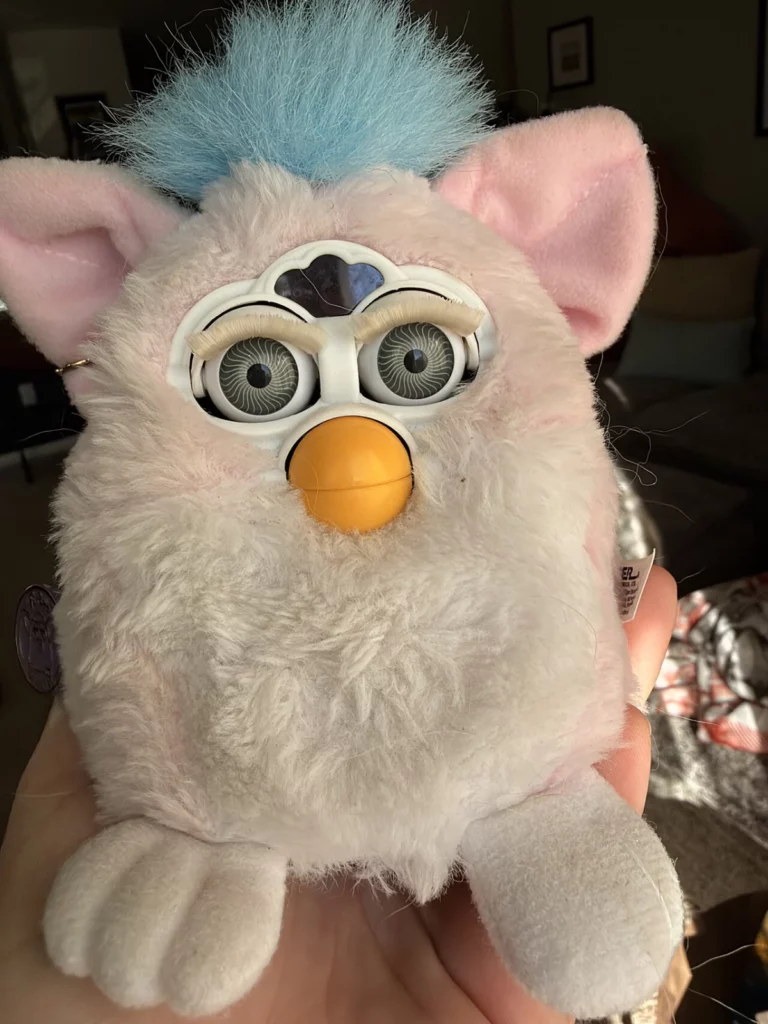 Un Furby Baby blanc et rose avec une touffe bleue